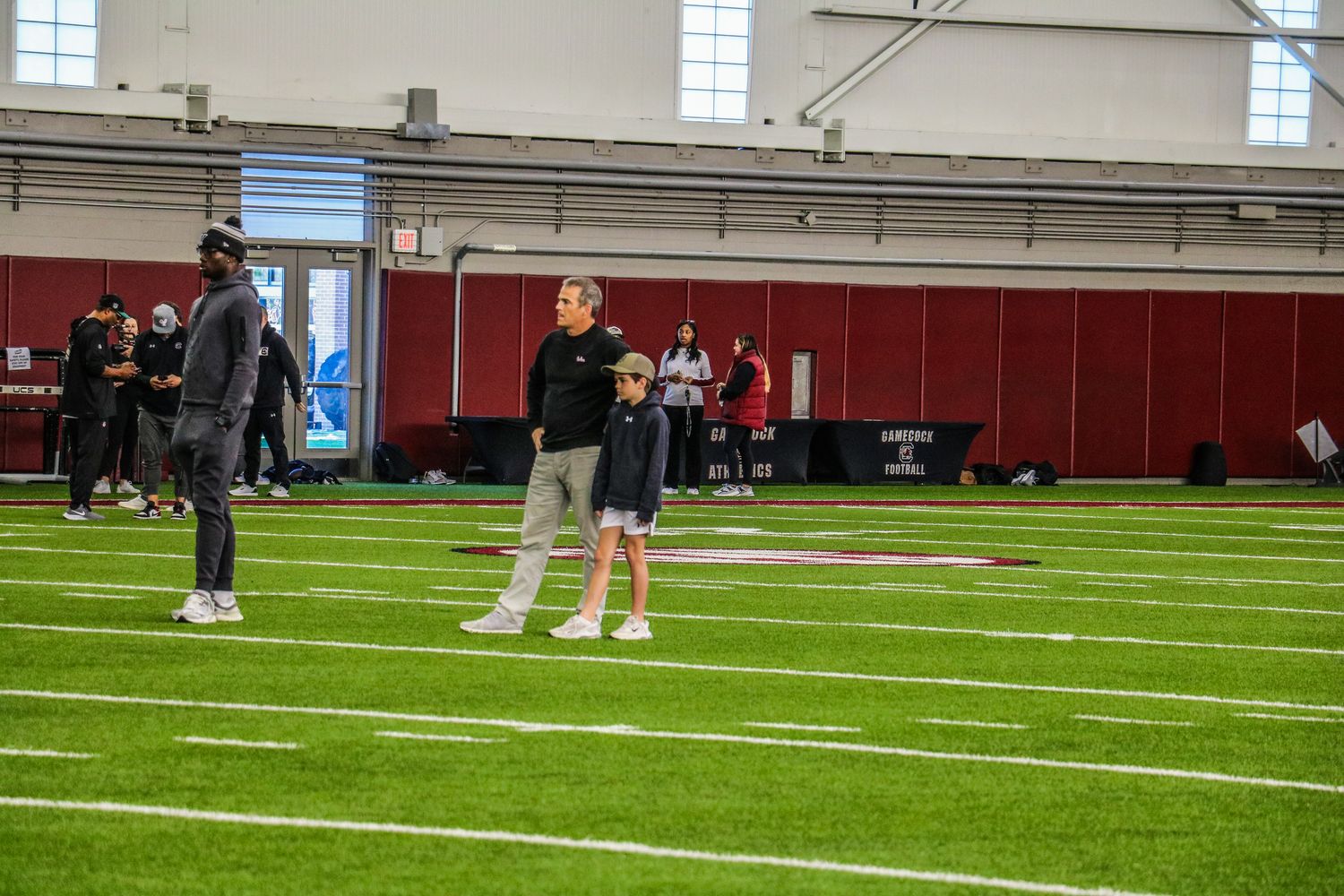 Nyck Harbor (left), head coach Shane Beamer (middle), and his son Hunter (right) watch the athletes go through some early athletic tests